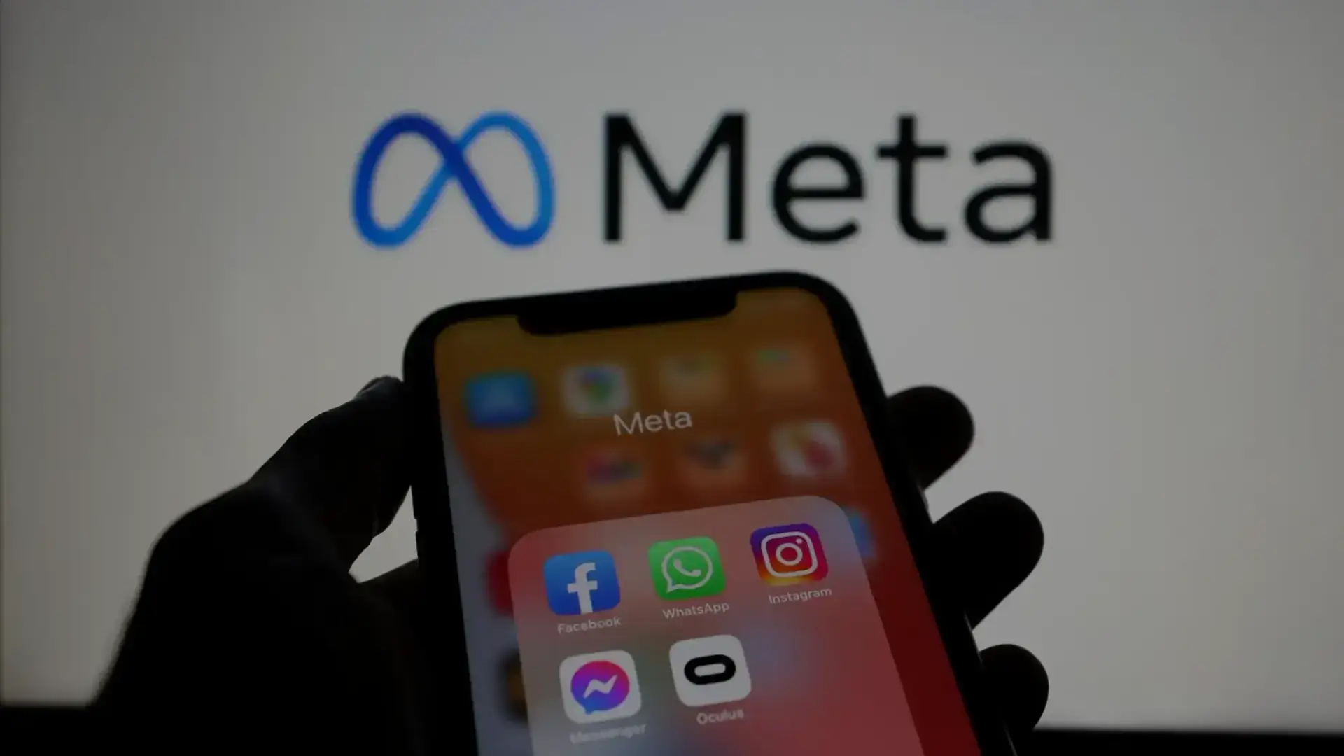 Meta logosunun önünde Facebook, WhatsApp, Instagram ve Messenger uygulamalarını gösteren telefon